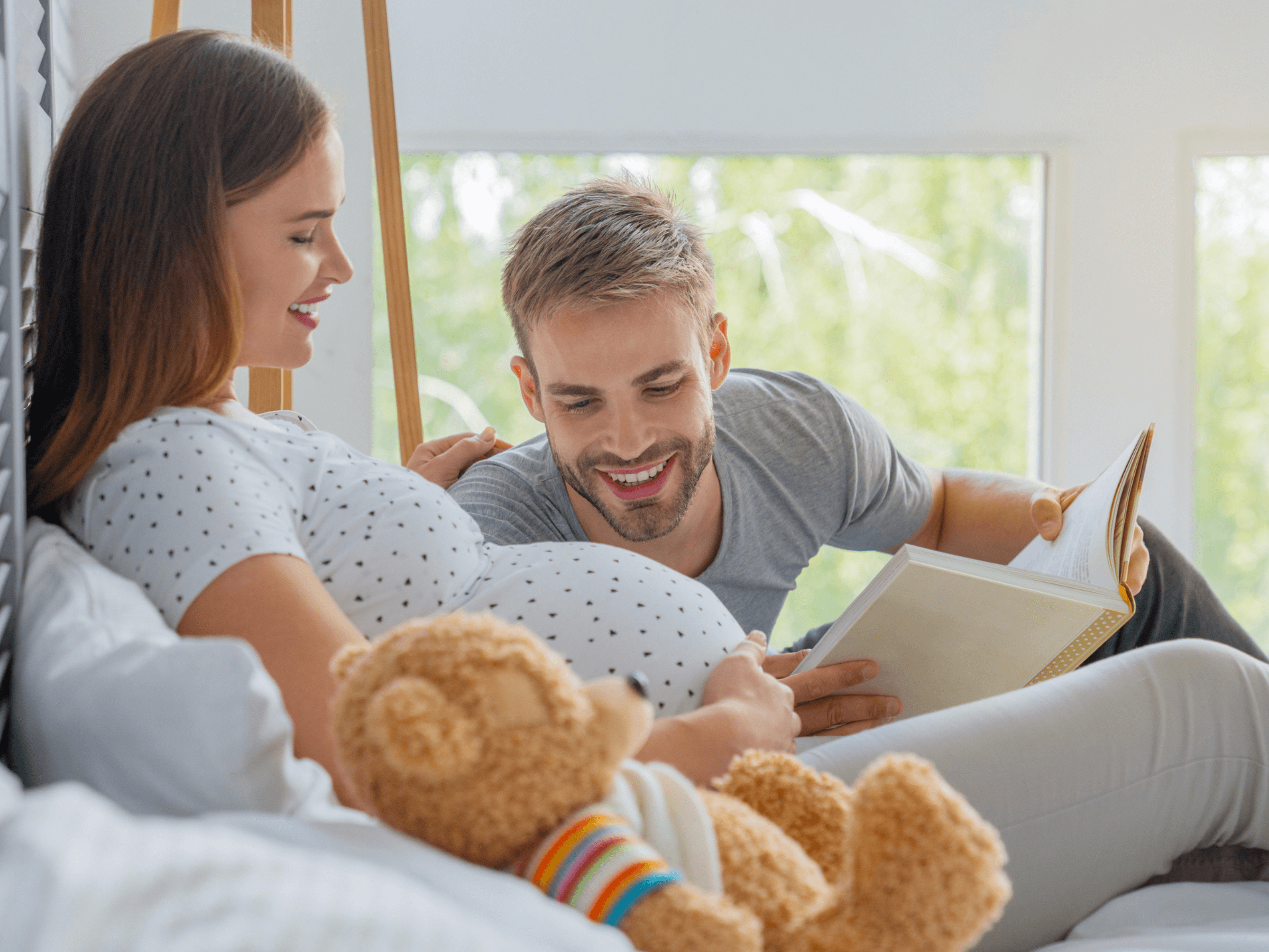 kobieta w ciąży ojciec czytają bajki na łóżku